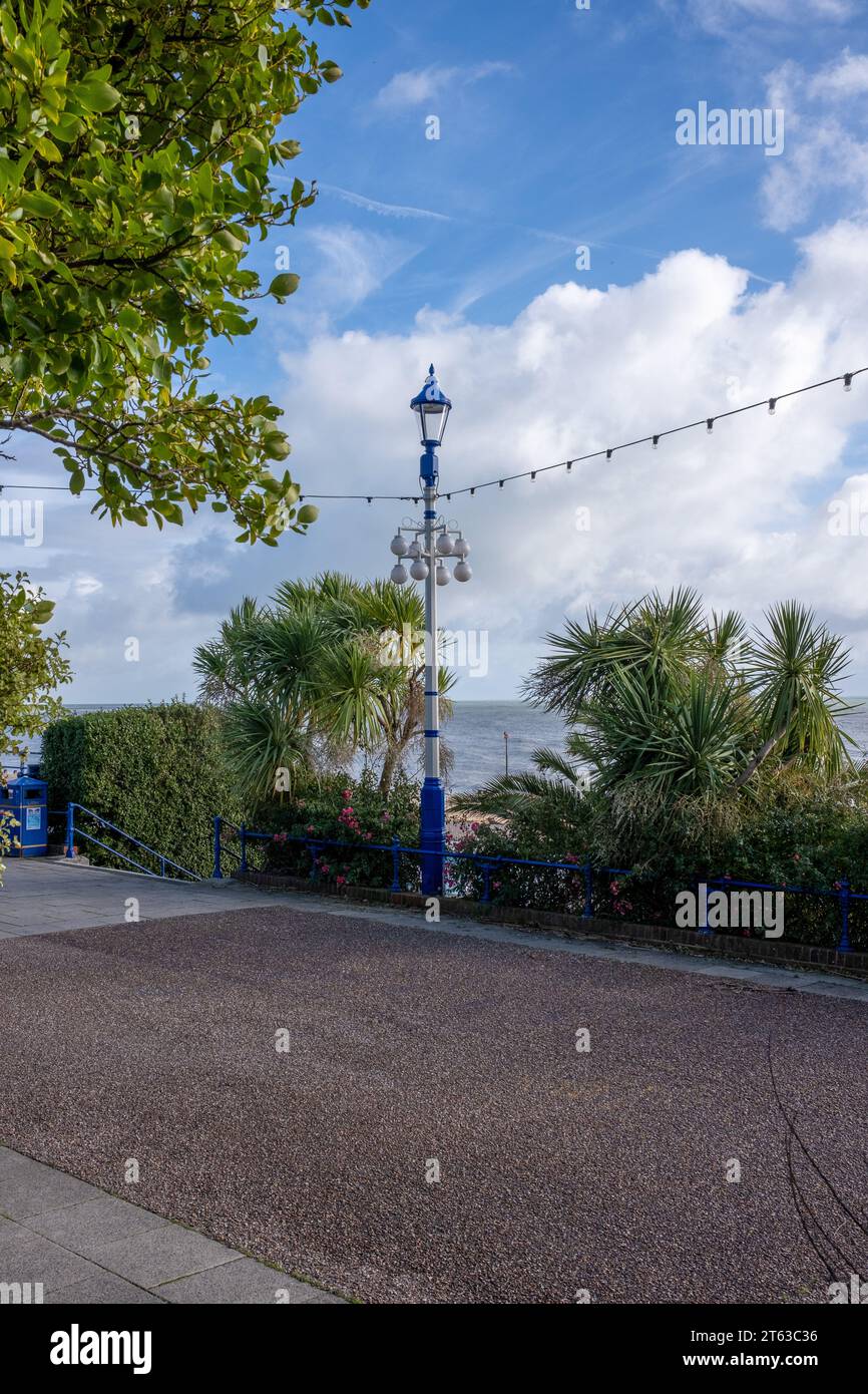 Lampost e luci su un lungomare deserto di Eastbourne sotto un cielo blu con nuvole Foto Stock