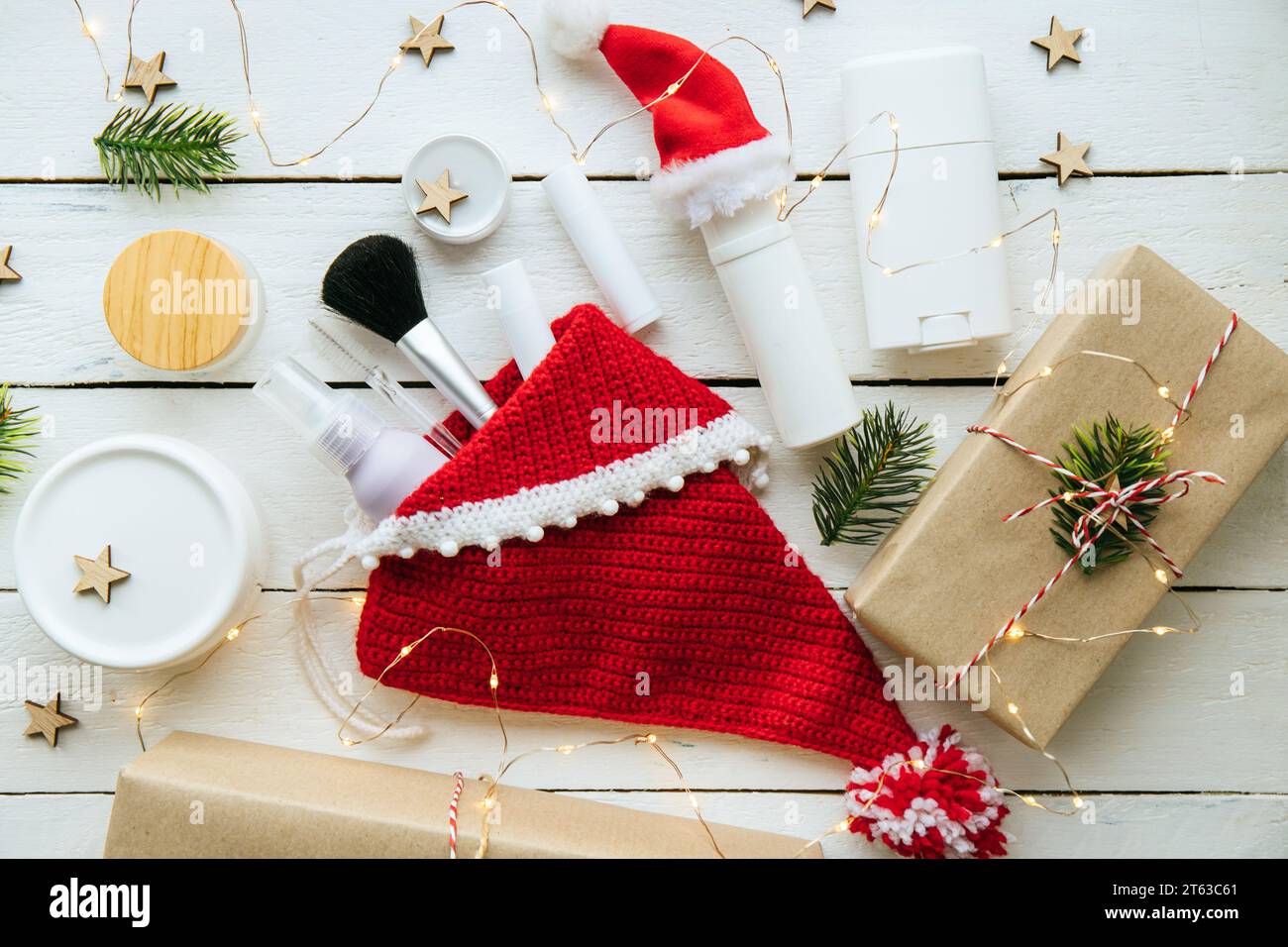 Prodotti di bellezza fatti a mano per il concetto di regalo di Natale. Vari vasi e bottiglie generici nelle calze di Natale e nei dintorni, decorati con luci. Foto Stock