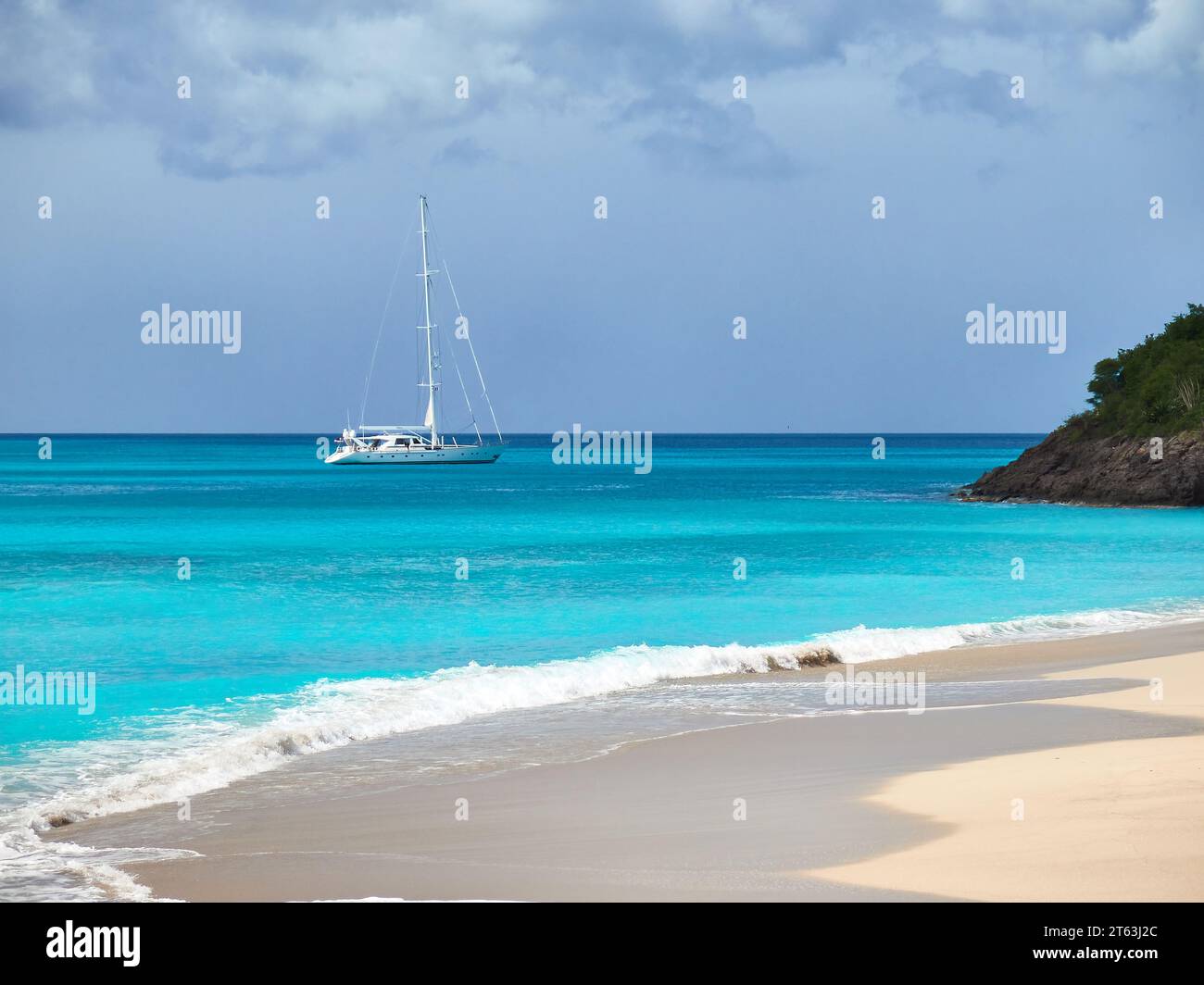 Lussuoso yacht a vela all'ancora al largo della spiaggia sabbiosa nelle acque turchesi della baia di Picarts sulla costa dell'isola di Antigua nei Caraibi. Foto Stock