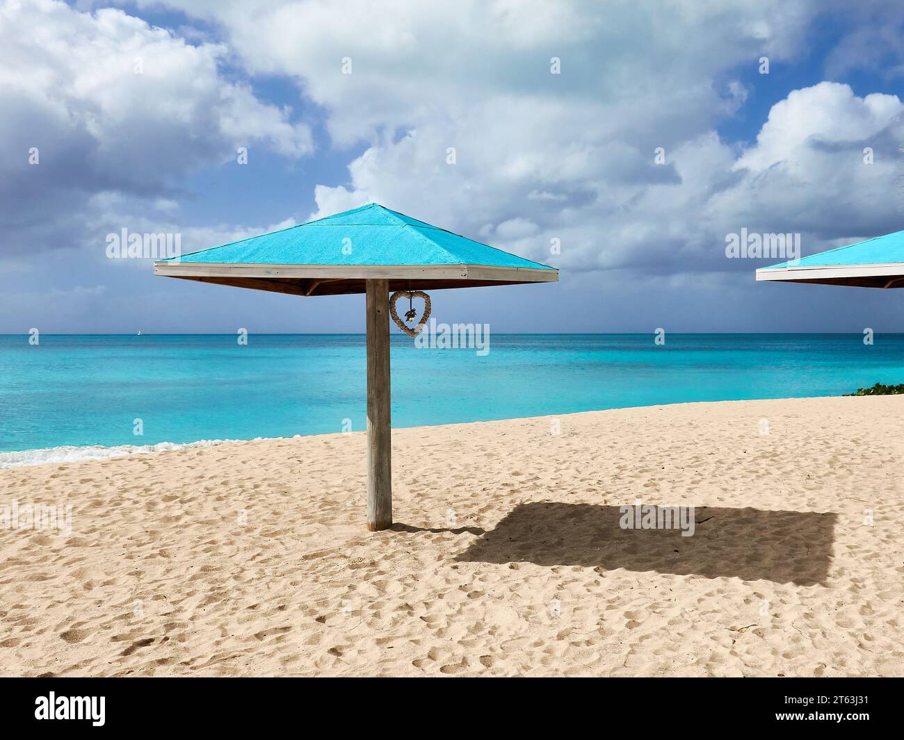 Ombrellone con cuore su una spiaggia di sabbia tropicale con un mare turchese. Foto Stock