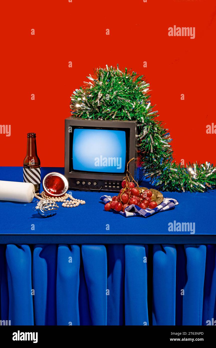 Ambientazione nostalgica con un vecchio televisore adornato da scintillanti pennarelli collocati su una superficie blu con diversi elementi e oggetti contro la b rossa Foto Stock