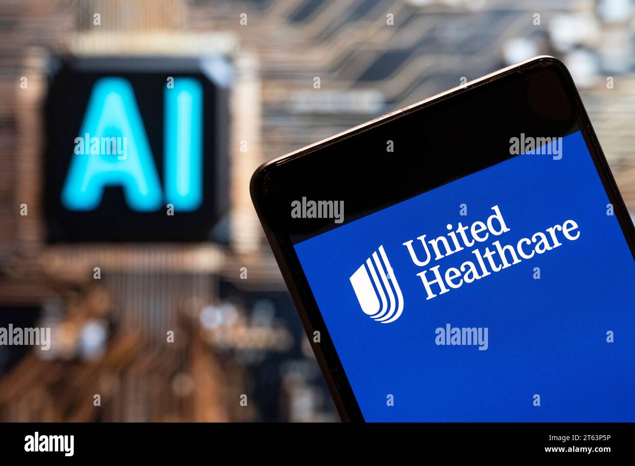 In questa immagine fotografica, il logo UnitedHealth della multinazionale americana gestita dalla società sanitaria e assicurativa è visualizzato su uno smartphone con un chip e un simbolo di intelligenza artificiale (ai) sullo sfondo. Foto Stock