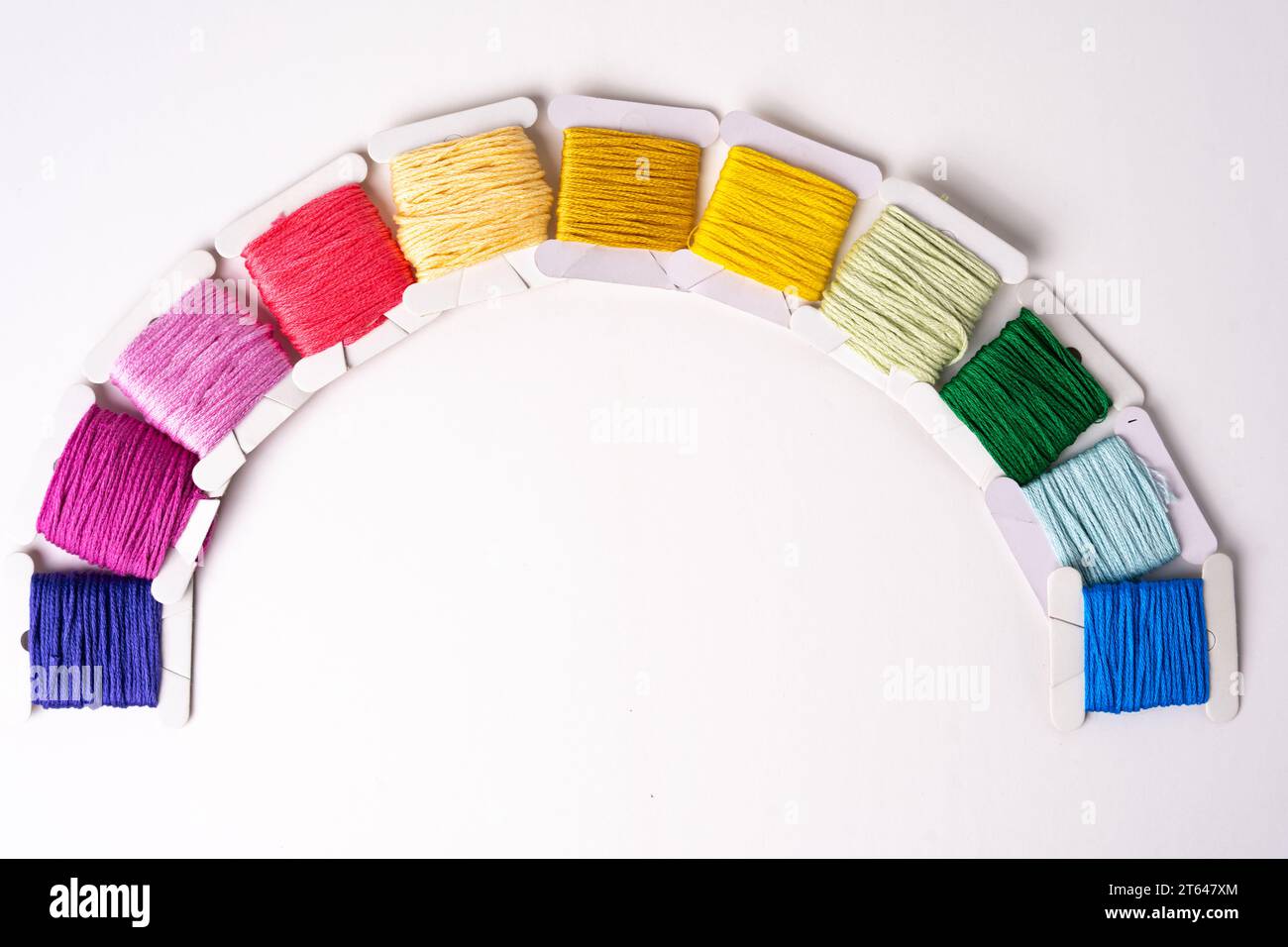 Diversi fili colorati e vivaci avvolti saldamente su piatti di cartone disposti come un arcobaleno Foto Stock