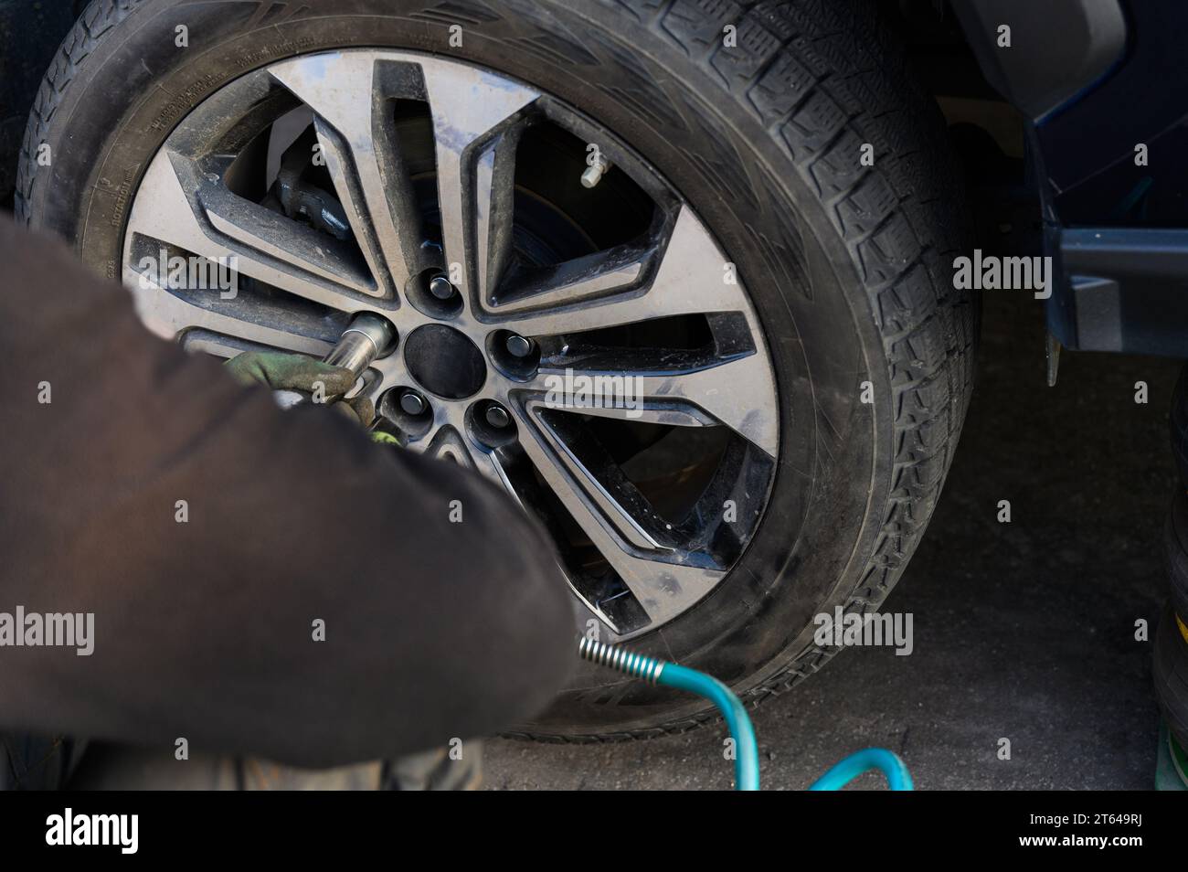 Meccanico di auto che cambia pneumatici in un'auto all'aperto Foto Stock