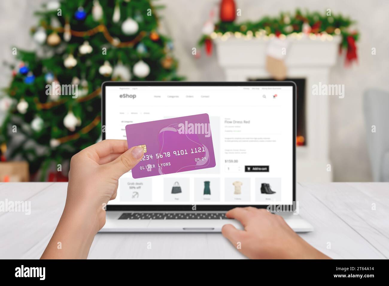 Shopping natalizio online su computer portatile con carta di credito. Albero di Natale e camino sullo sfondo Foto Stock