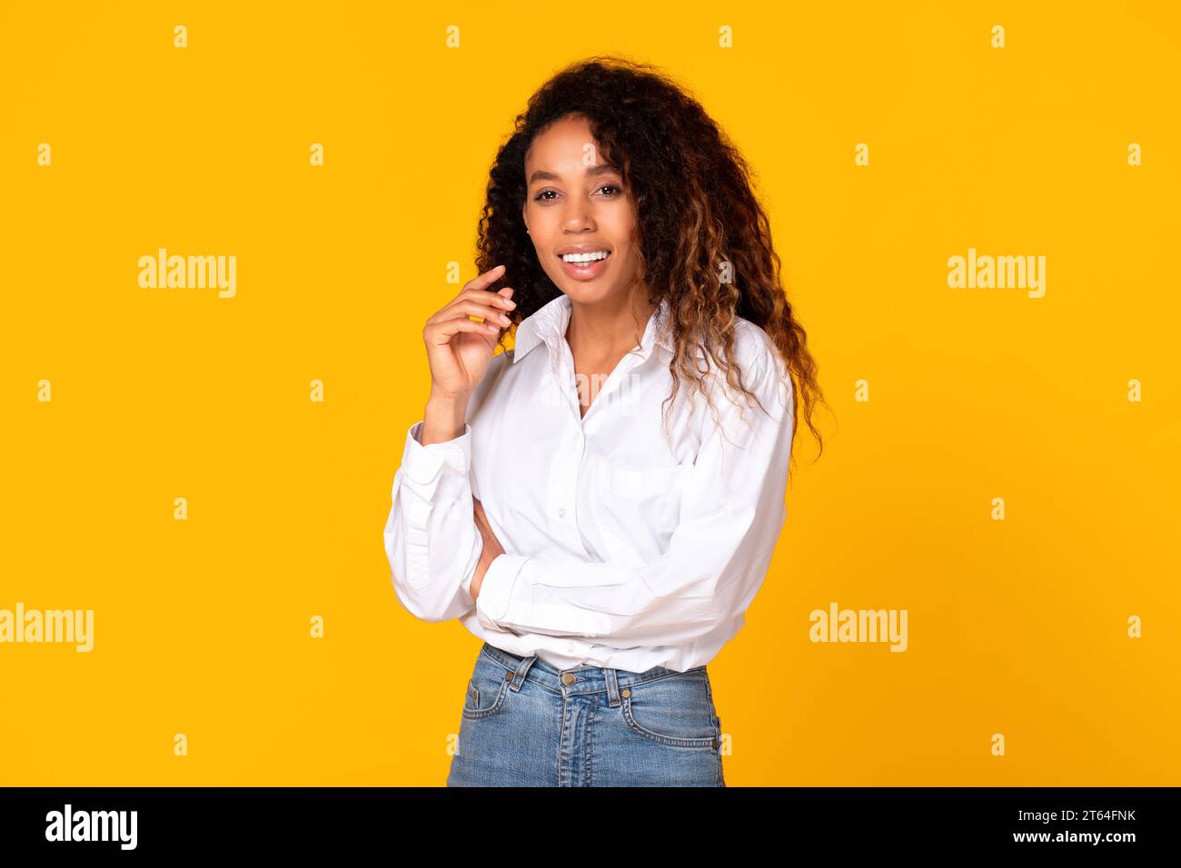 Giovane donna afro-americana che posa in mostra un bel sorriso, studio giallo Foto Stock