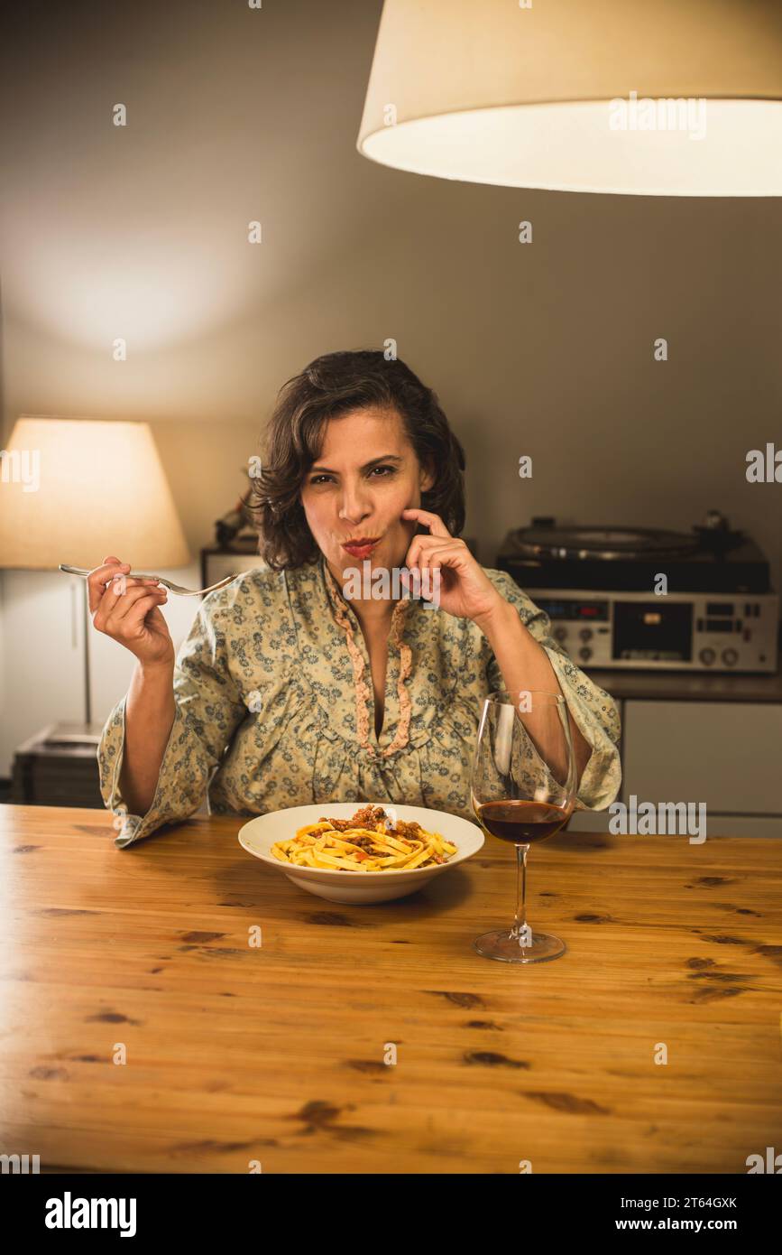 Donna che mangia un piatto di tagliatelle al Ragu bolognese in un'accogliente sala da pranzo. Foto Stock