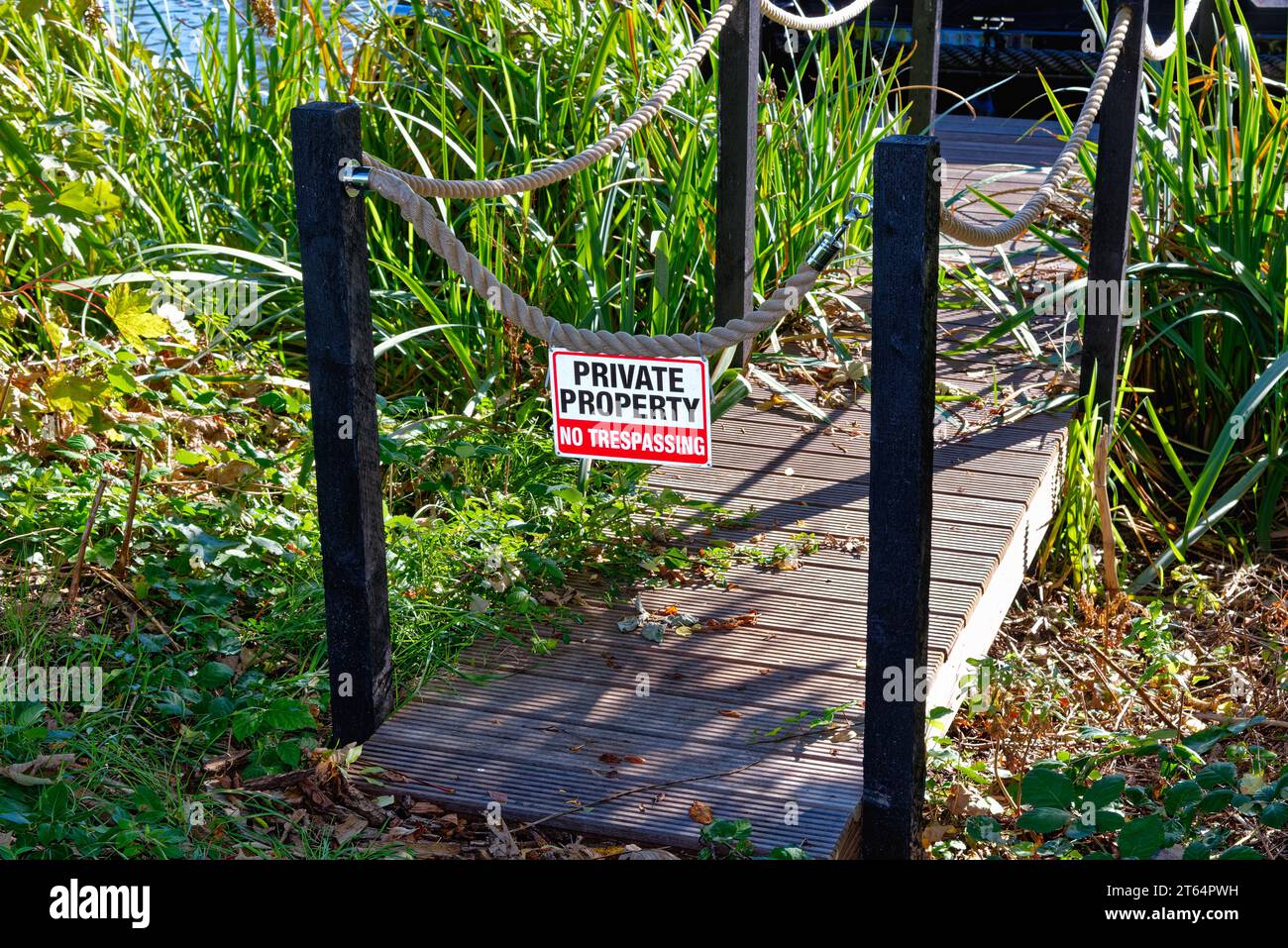 Un cartello con la scritta Private Property No Trespassing appeso da una corda su un piccolo molo vicino al Tamigi, Surrey Inghilterra Regno Unito Foto Stock