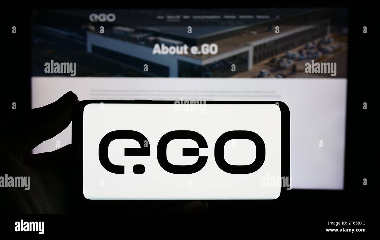 Persona che possiede uno smartphone con il logo della società tedesca di veicoli elettrici Next.e.GO Mobile se davanti al sito Web. Concentrarsi sul display del telefono. Foto Stock