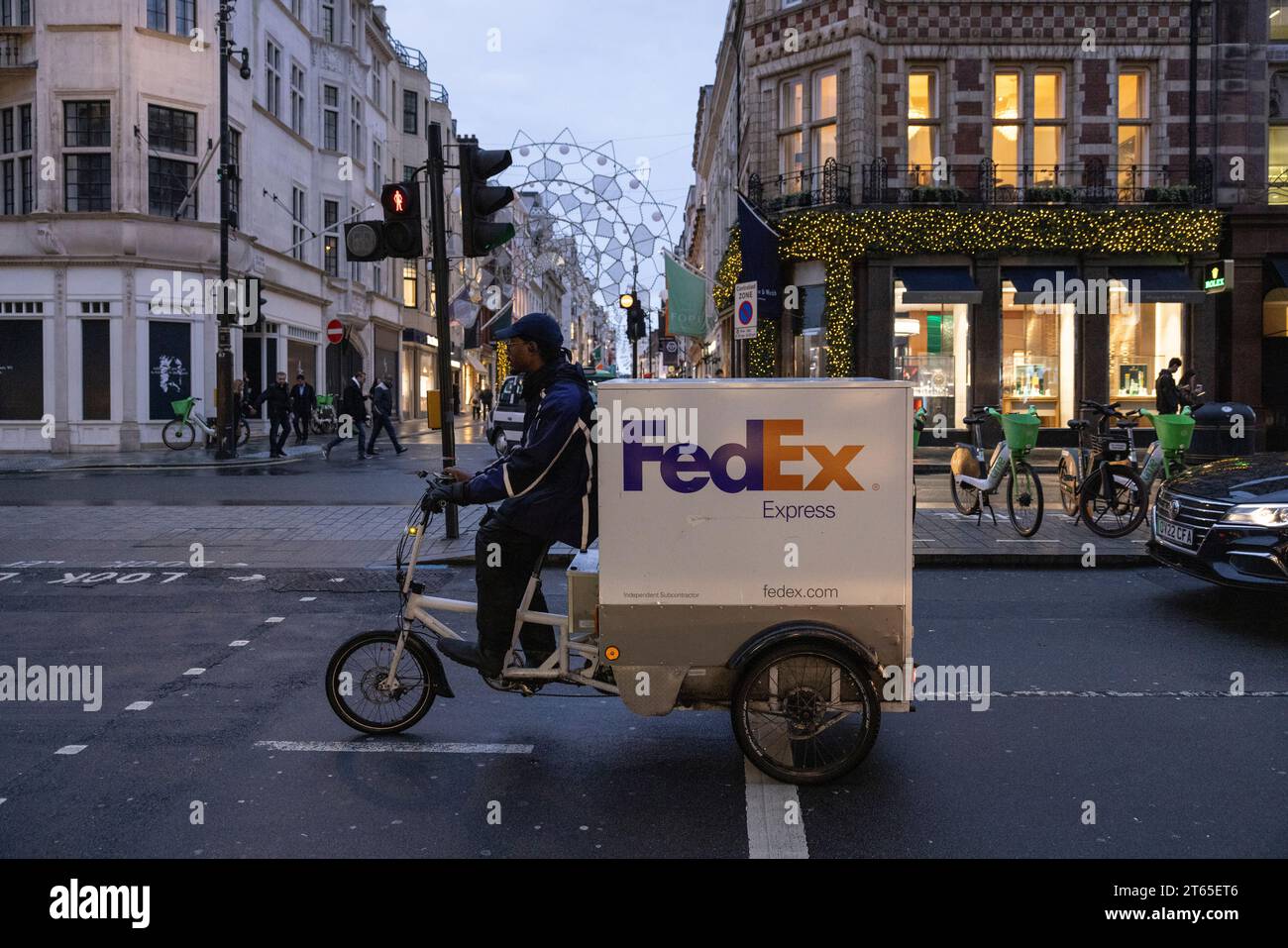 Corriere FedEx in bicicletta lungo Piccadilly su un trike e-cargo, Mayfair, centro di Londra, Inghilterra, Regno Unito Foto Stock Corriere FedEx in bicicletta lungo Piccadilly su un trike e-cargo, Mayfair, centro di Londra, Inghilterra, Regno Unito Foto Stock