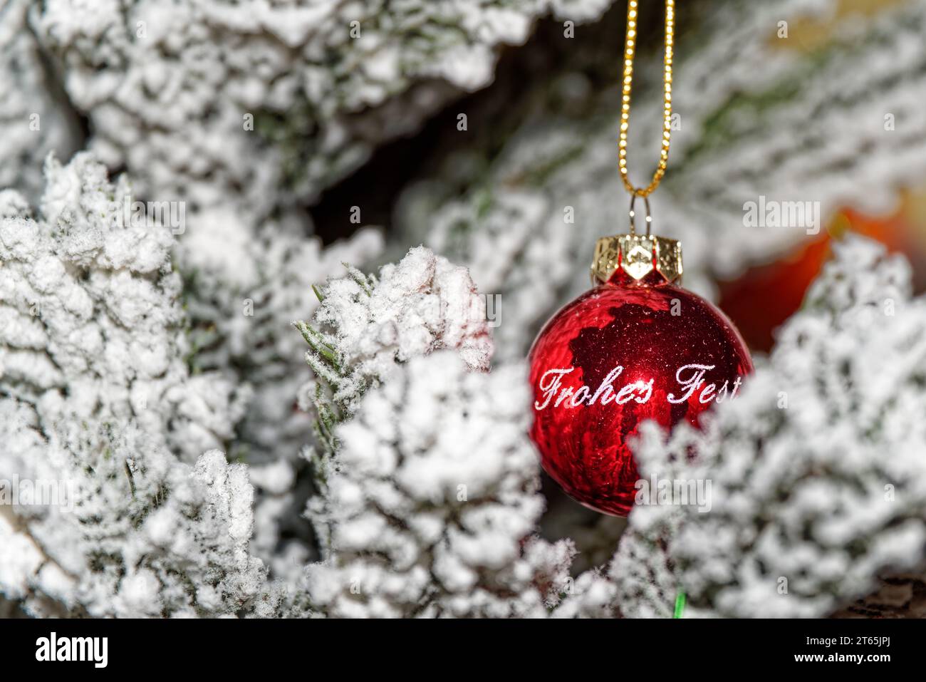 Red palla di Natale con Happy Holiday testo in tedesco appeso sul ramo di abete Foto Stock