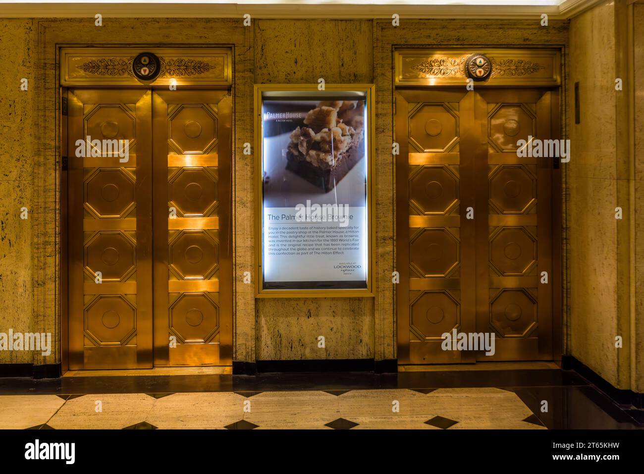 Ascensori dorati nella Palmer House, costruiti nel 1873. Il Palmer House è stato il primo hotel di Chicago con ascensori. Insegna illuminata che pubblicizza la famosa pasticceria, il brownie inventato da Bertha Palmer. Per l'esposizione universale del 1893, l'ormai famoso brownie fu creato nella Palmer House di Chicago. E' ancora oggi offerto nel suo luogo di origine, la Lockwood Patisserie nella Palmer House, parte della catena Hilton. Chicago, Illinois, Stati Uniti Foto Stock
