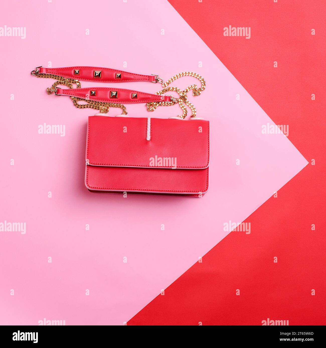 Moderna borsa femminile in pelle rossa con catena a spalla dorata isolata su uno sfondo grafico rosa-rosso con spazio per la copia. Poster promozione sconto per una e Foto Stock