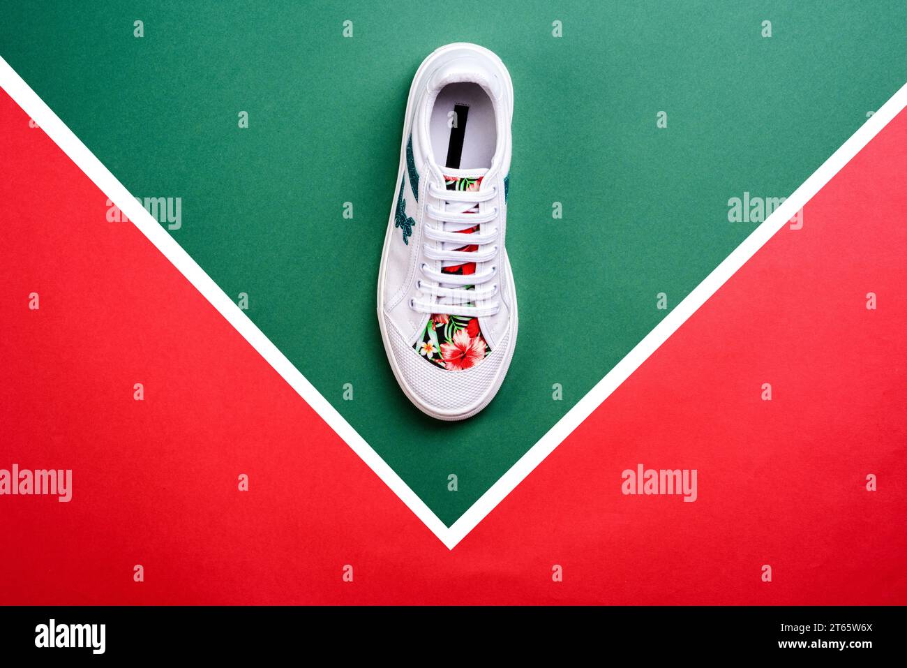 Moderna sneaker da donna in pelle bianca con puntale e luminoso inserto con stampa tropicale, isolata su uno sfondo multicolore a contrasto con spazio per la copia Foto Stock