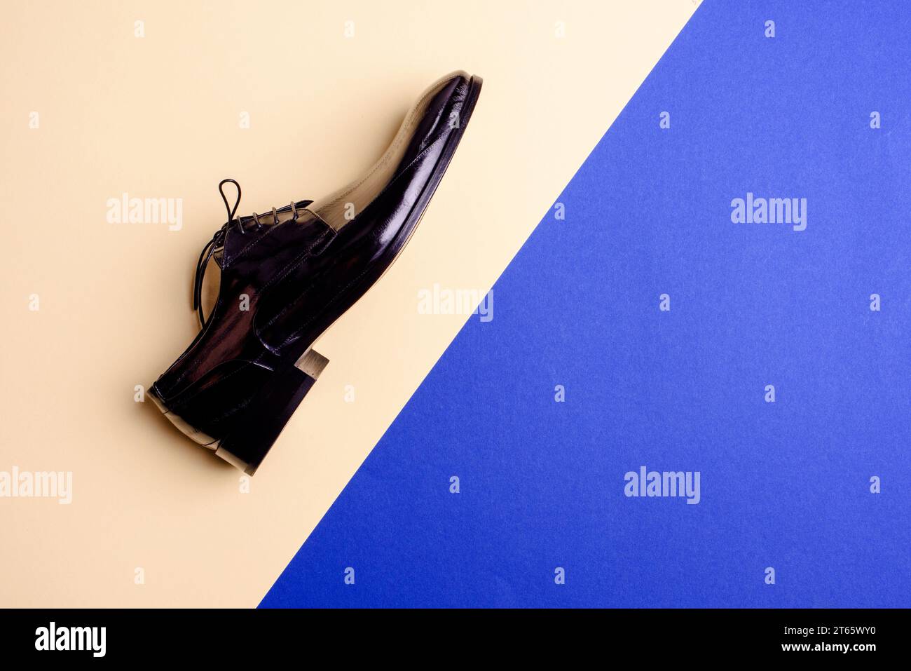 Elegante scarpa maschile in pelle verniciata nera su sfondo blu con spazio libero per l'annuncio. Blog o rivista di moda maschile. Poster pubblicitario del negozio di scarpe. Footw Foto Stock