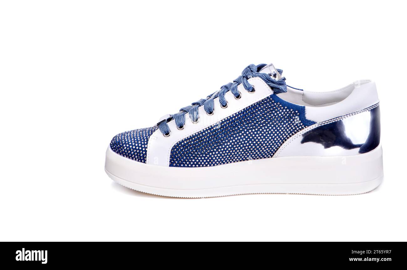 Sneaker bianca e blu glamour con strass e bancone metallico lucido isolato su uno sfondo bianco. Stile e tendenza. Pubblicità per scarpe Foto Stock