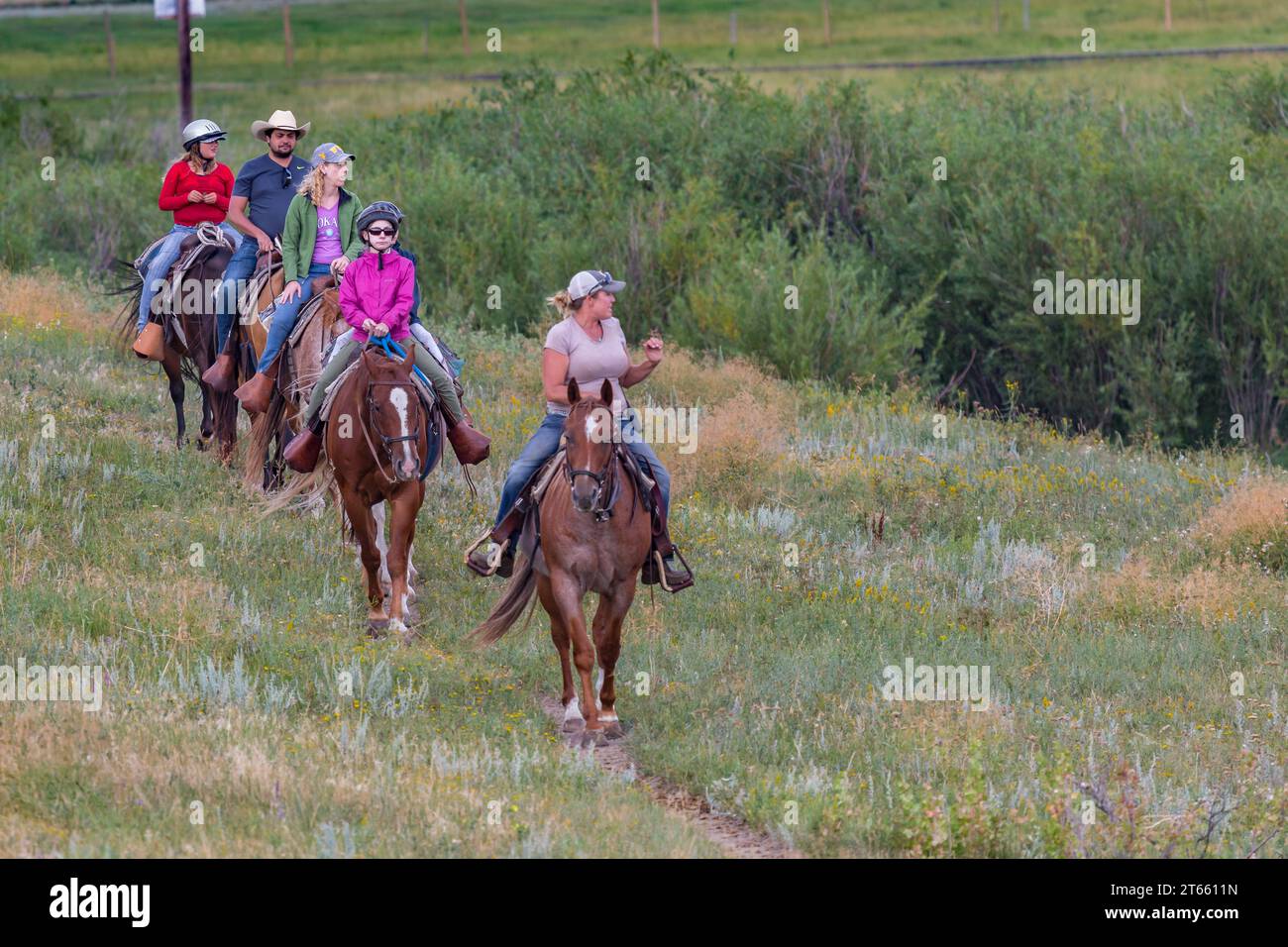 La tua famiglia è guidata da un'escursione a cavallo attraverso i campi del Terry Bison Ranch vicino a Cheyenne, Wyoming Foto Stock