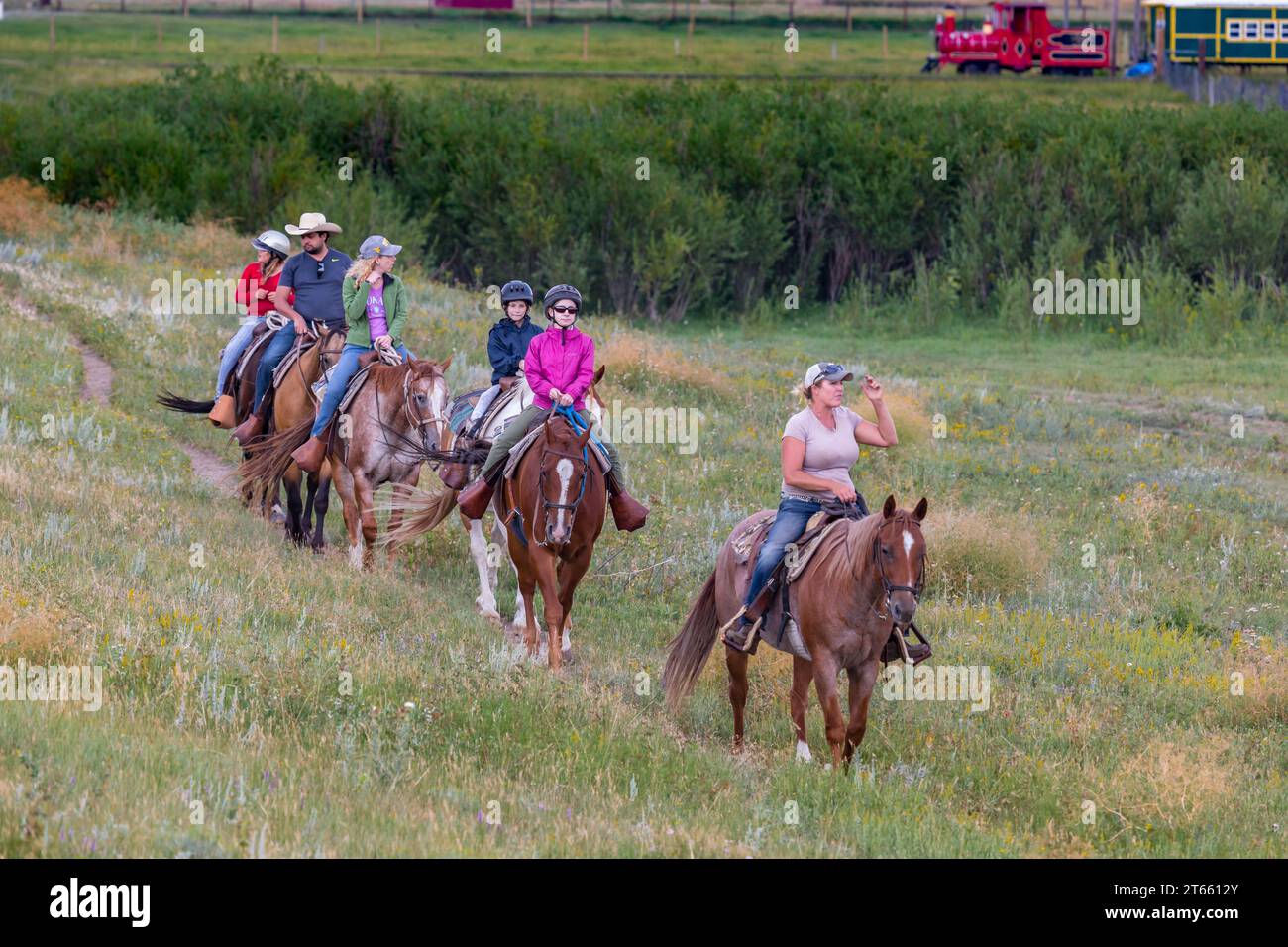 La tua famiglia è guidata da un'escursione a cavallo attraverso i campi del Terry Bison Ranch vicino a Cheyenne, Wyoming Foto Stock