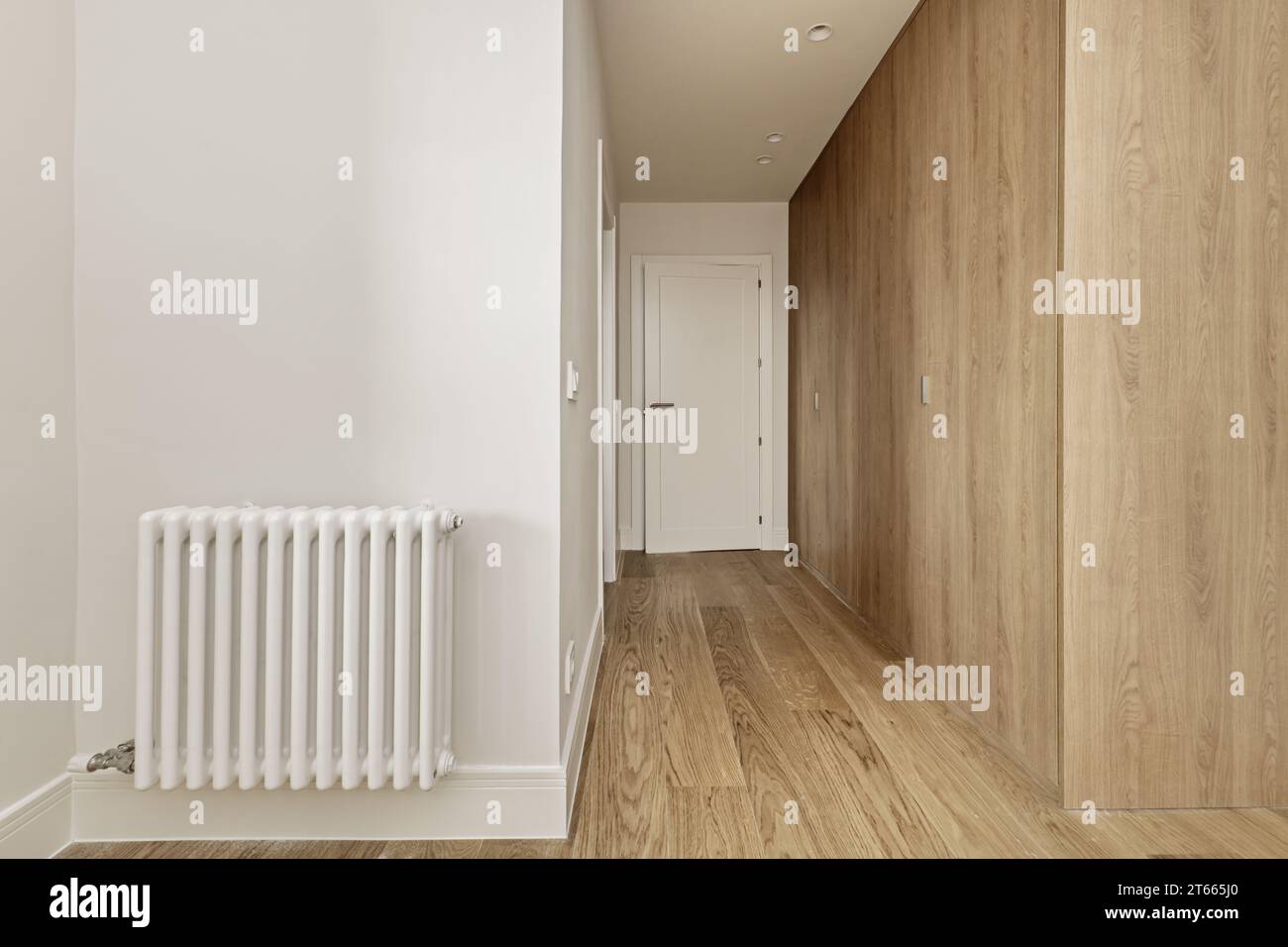 Dall'ingresso ad una camera da letto con guardaroba accessoriati con porte in legno di quercia chiaro fatte su misura con accesso ad un bagno privato Foto Stock