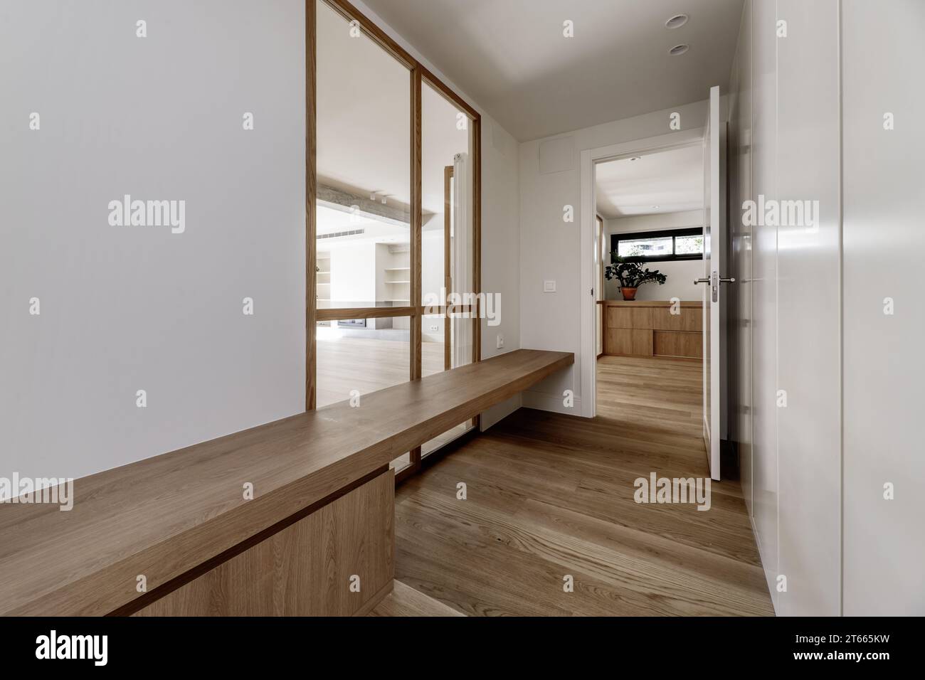 Corridoio di una casa residenziale con una lunga panca in legno con cassetti sotto, una finestra di vetro Foto Stock