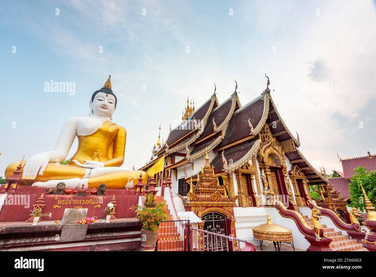 La grande statua iconica in oro e bianco del Buddha seduto, si affaccia su uno spazio esterno all'edificio principale, accanto alla strada principale del perimetro della città Vecchia Foto Stock