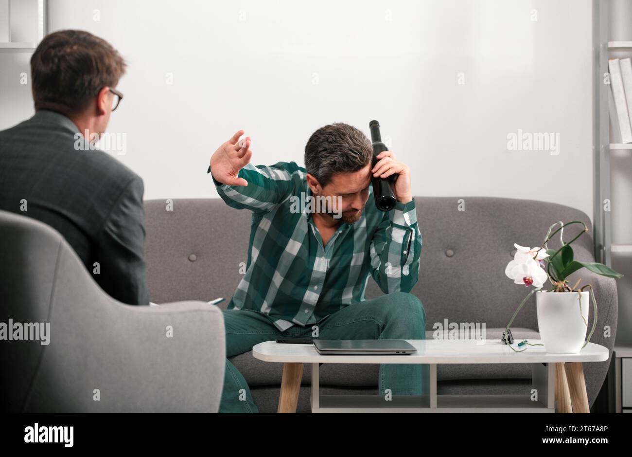 Uomo depresso con bottiglia di vino in sessione di psicoterapia. Abuso delle persone e problemi di alcolismo. Psicologia, concetto di terapia mentale. Foto Stock