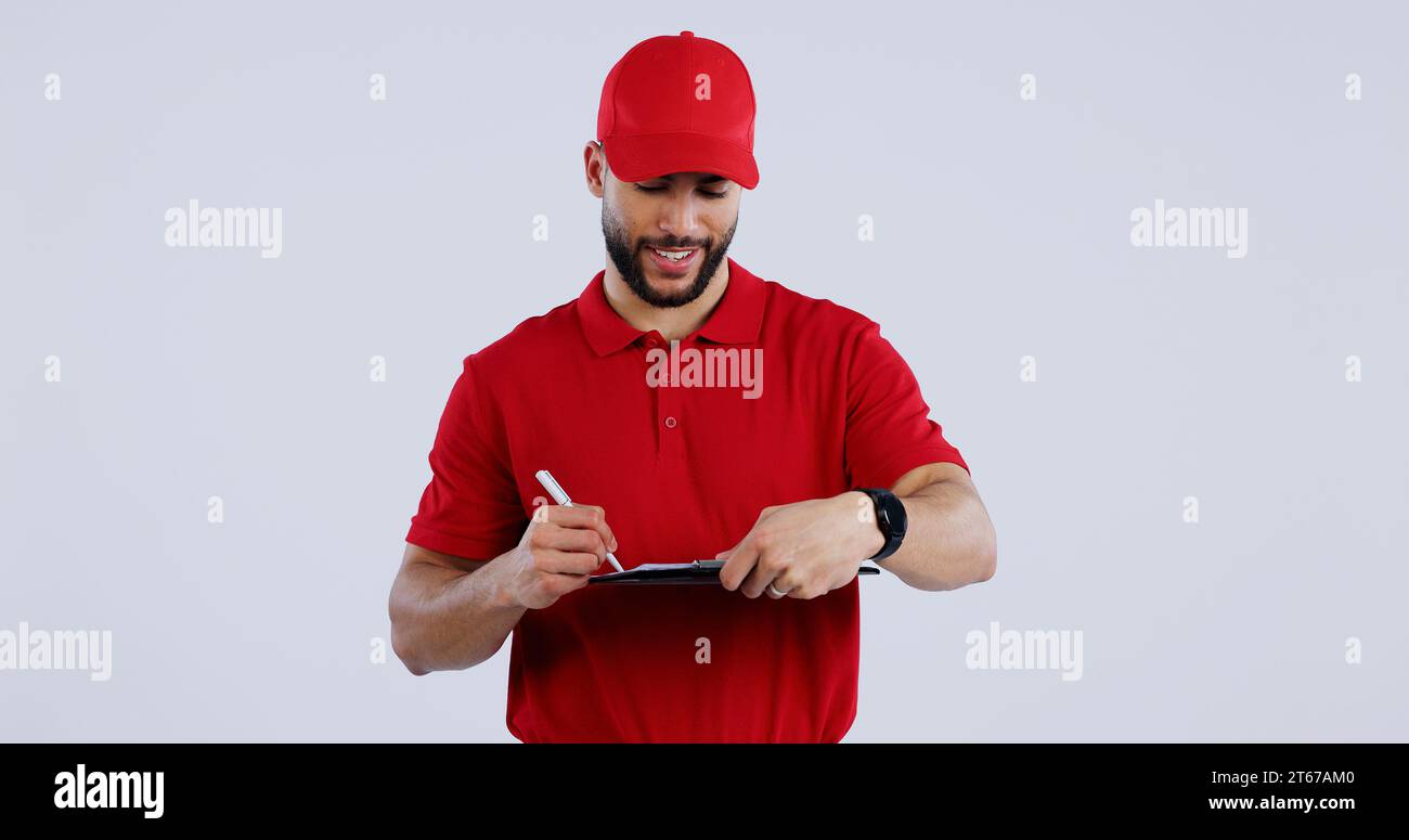 Uomo felice, consegna e scrittura sugli appunti per la firma, l'ordine o il modulo sullo sfondo di uno studio. Persona maschile o persona del servizio di corriere sorride per Foto Stock