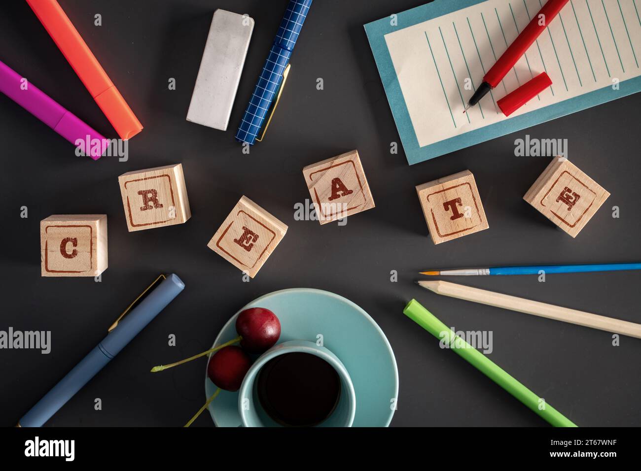Piano di una scrivania creativa con 'CREATE' scritto in blocchi di legno, circondato da forniture artigianali e una tazza di caffè. Foto Stock