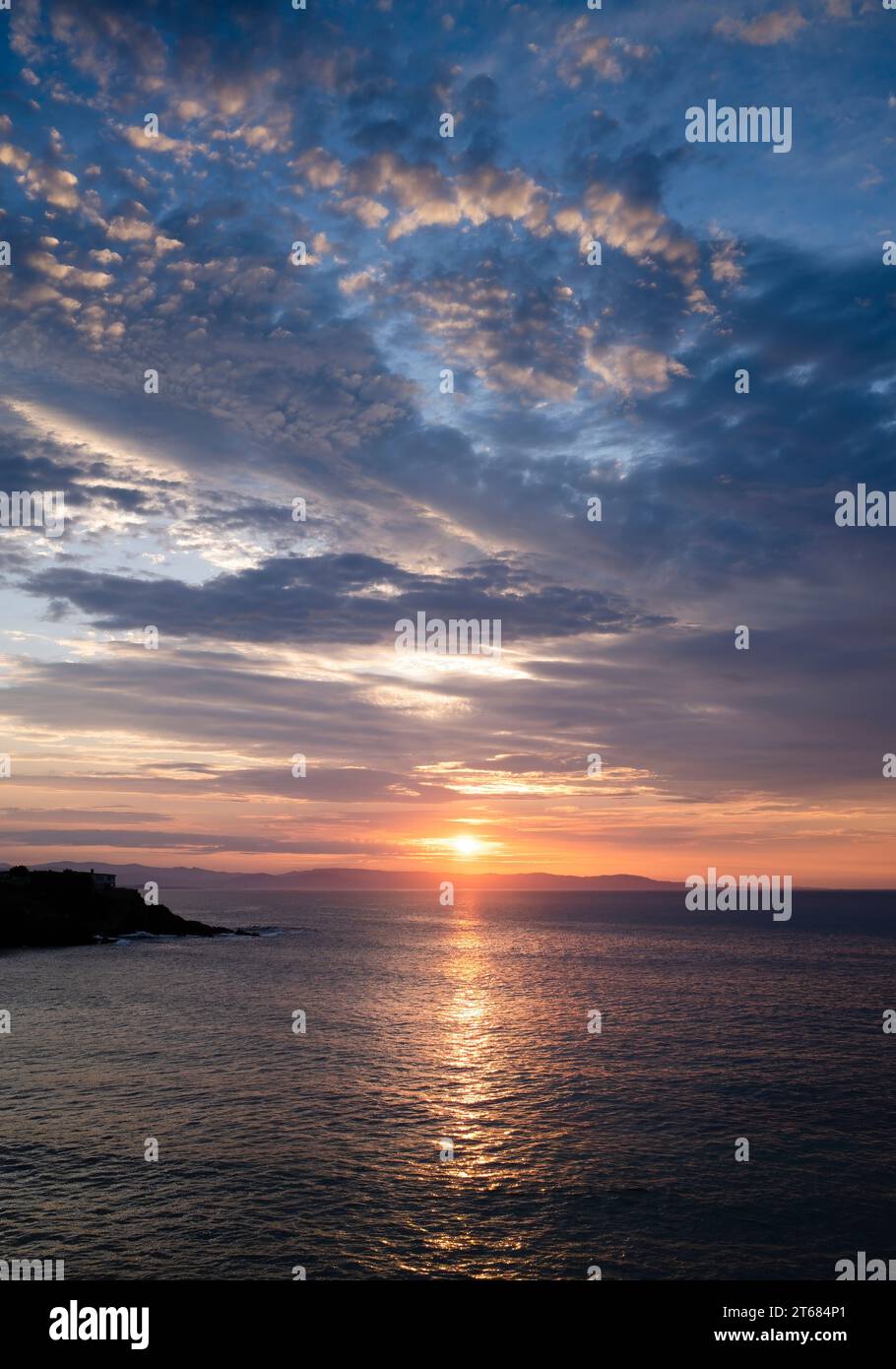 Paesaggio al tramonto tra le nuvole sull'orizzonte del mare. Riflessi dorati nelle nuvole e nel mare. Foto Stock