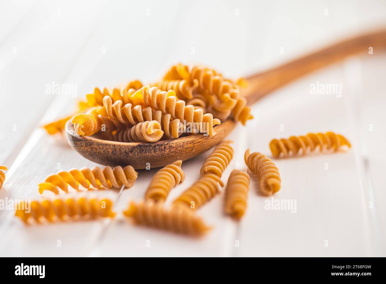 Pasta fusilli cruda a grani interi. Pasta cruda sul cucchiaio di legno. Foto Stock
