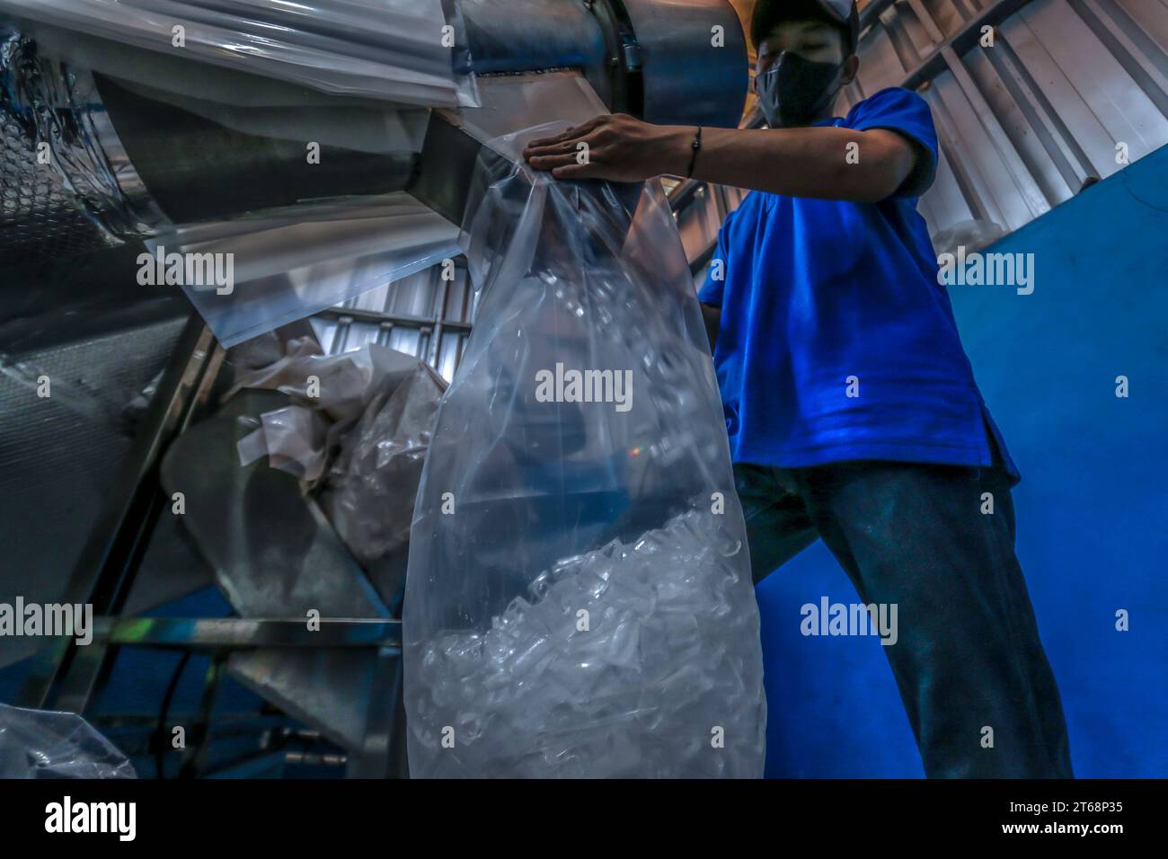 I lavoratori confezionano cubetti di ghiaccio di cristallo in una fabbrica di cubetti di ghiaccio di cristallo a Bogor, Giava Occidentale, Indonesia, il 31 ottobre 2023 Foto Stock