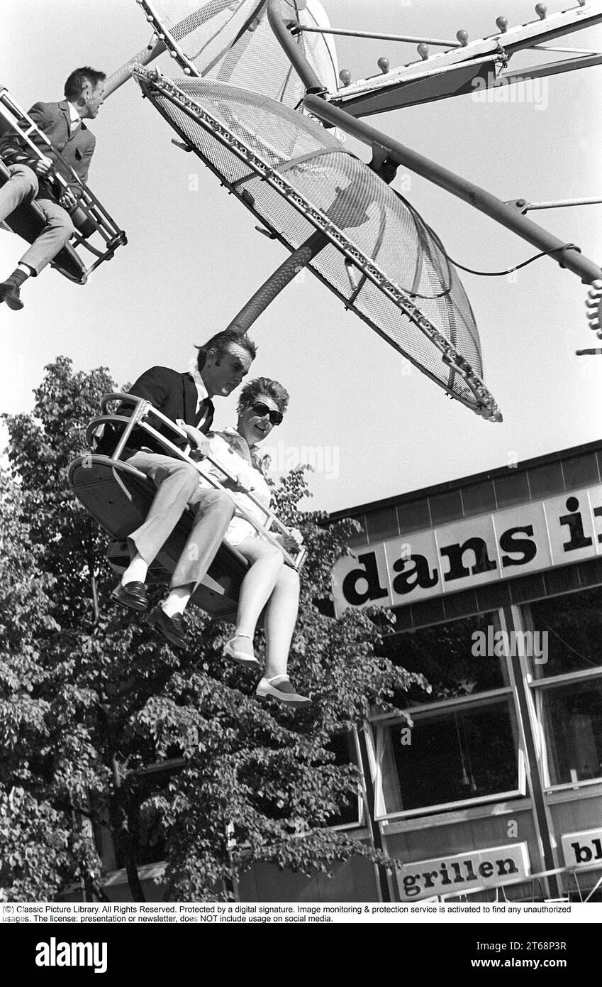 Parco divertimenti negli anni '1960 Una coppia e' vista in una delle attrazioni che vengono offerte sul terreno. Si siedono uno accanto all'altro in un posto che si muove intorno a sé. Svezia 1968 Foto Stock