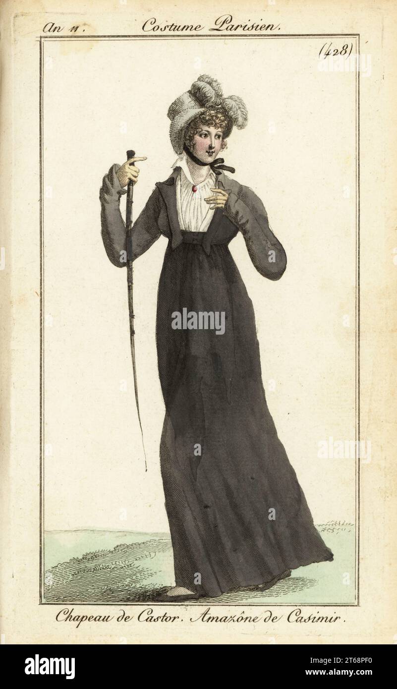 Donna parigina in abito da equitazione, 1803. Indossa un cappello in pelle di castoro con pennacchio, un abito da equitazione in lana di cashmere e tiene un raccolto di cavalcate. Chapeau de Castor. Amazone de casimir incisione in copperplate a mano da Pierre de la Mesangeres Journal des Dames et des Modes, Magazine of Women and Fashion, Paris, An 11, 1803. Illustrazioni di Carle Vernet, Jean-Francois Bosio, Dominique Bosio e Philibert Louis Debucourt, incise da Pierre-Charles Baquoy. Foto Stock