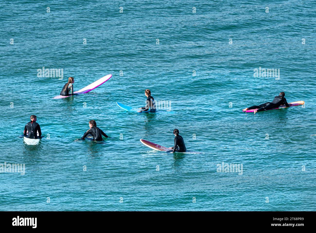 I surfisti galleggiano sulle loro tavole da surf in attesa di un'onda a Fistral a Newquay, in Cornovaglia, nel Regno Unito. Foto Stock