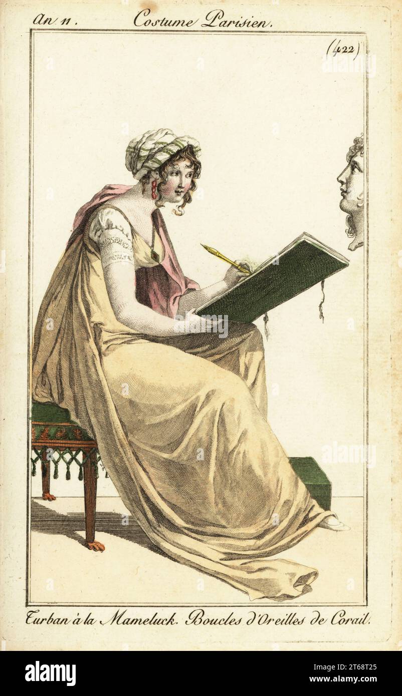 Donna che disegna un busto classico in un bozzetto, 1802. Indossa un turbante mamelucco, orecchini di corallo e un lungo abito in bronzo. Turban à la Mameluck. Boucles d'Oreilles de Corail. Incisione su copperplate a mano dal suo Pierre de la Mesangeres Journal des Dames et des Modes, Magazine of Women and Fashion, Parigi, 27 ottobre 1802. Illustrazioni di Carle Vernet, Jean-Francois Bosio, Dominique Bosio e Philibert Louis Debucourt, incise da Pierre-Charles Baquoy. Foto Stock