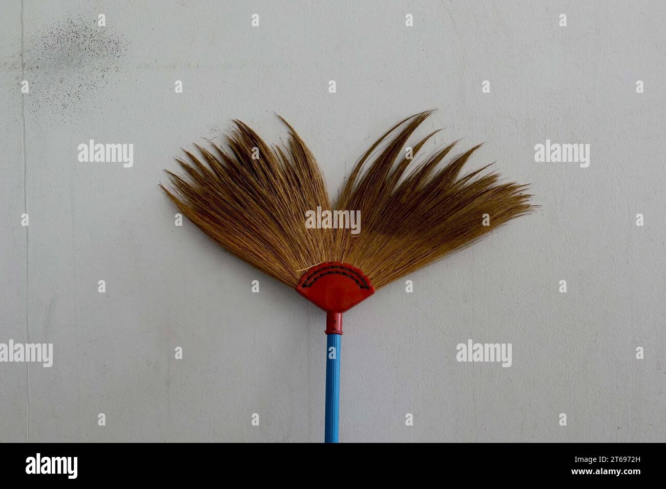 Scopa sulla parete bianca, pulizia e lavoro domestico. Foto Stock
