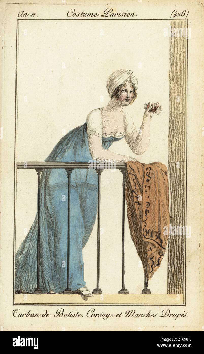 Donna sul balcone del teatro in turbante cambric. Tiene un vetro d'opera, indossa un vestito con corpetto smerlato e maniche, e poggia il suo scialle sulla balaustra. Turban de Batiste. Corsage et Manches Drapés. Incisione in copperplate a mano da Pierre de la Mesangeres Journal des Dames et des Modes, Magazine of Women and Fashion, Paris, An 11, 1803. Illustrazioni di Carle Vernet, Jean-Francois Bosio, Dominique Bosio e Philibert Louis Debucourt, incise da Pierre-Charles Baquoy. Foto Stock