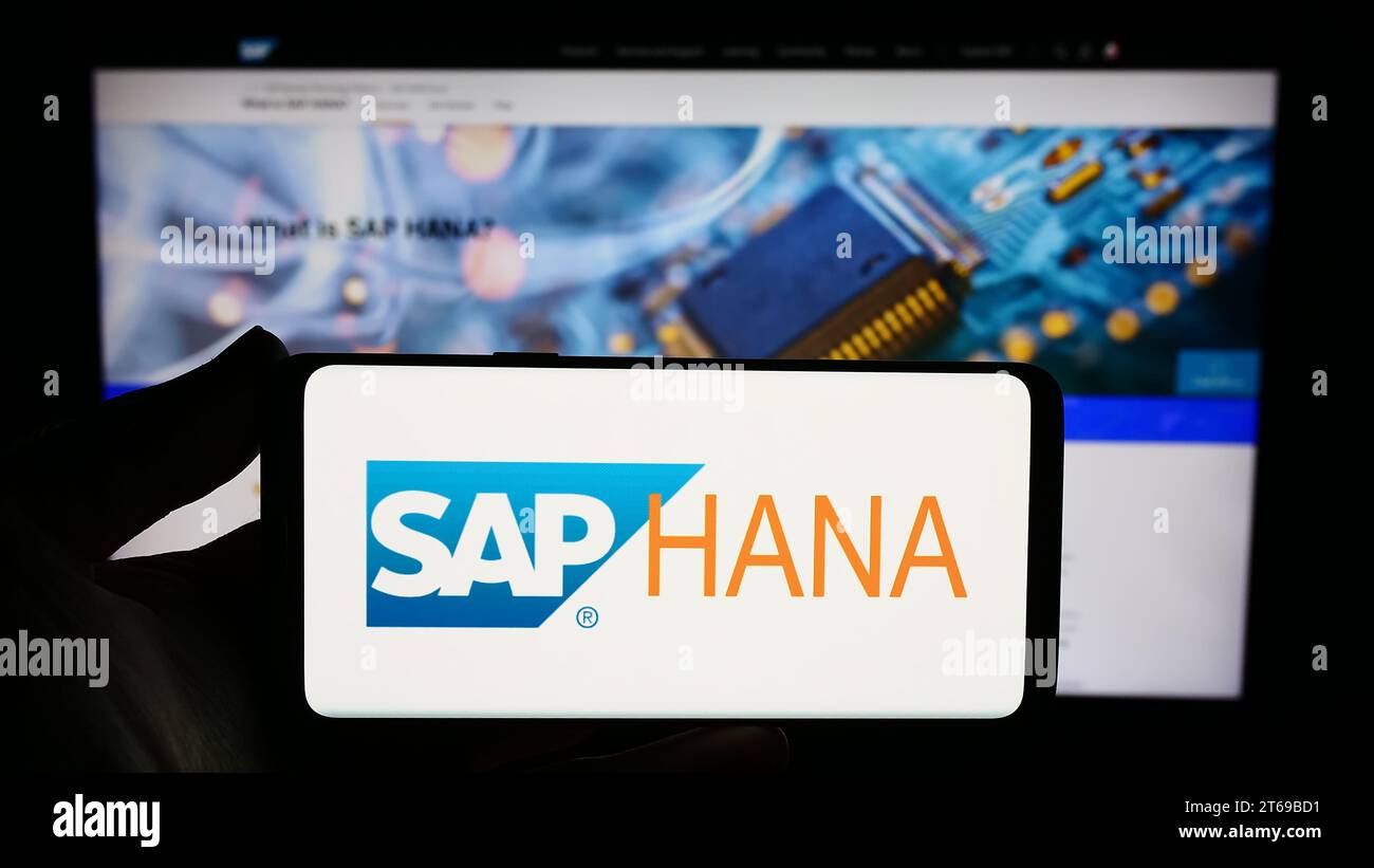 Persona che possiede uno smartphone con il logo del software di gestione del database SAP HANA davanti al sito Web. Concentrarsi sul display del telefono. Foto Stock