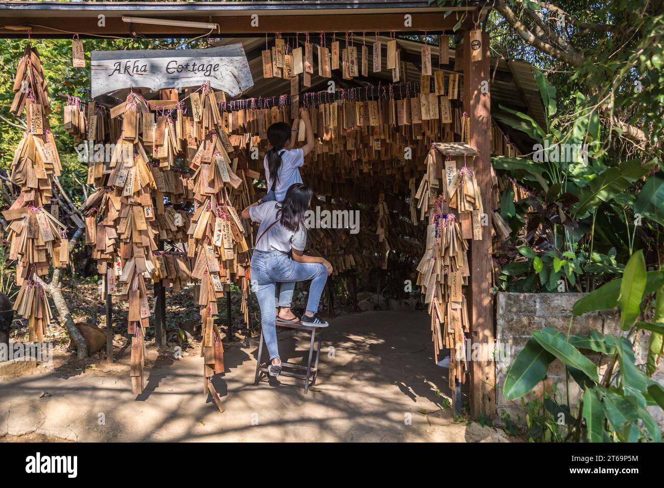 Le donne thailandesi appendono la loro targa di messaggio personale vicino all'ingresso del ristorante e caffetteria Akha Cottage a Chiang Rai, Thailandia Foto Stock