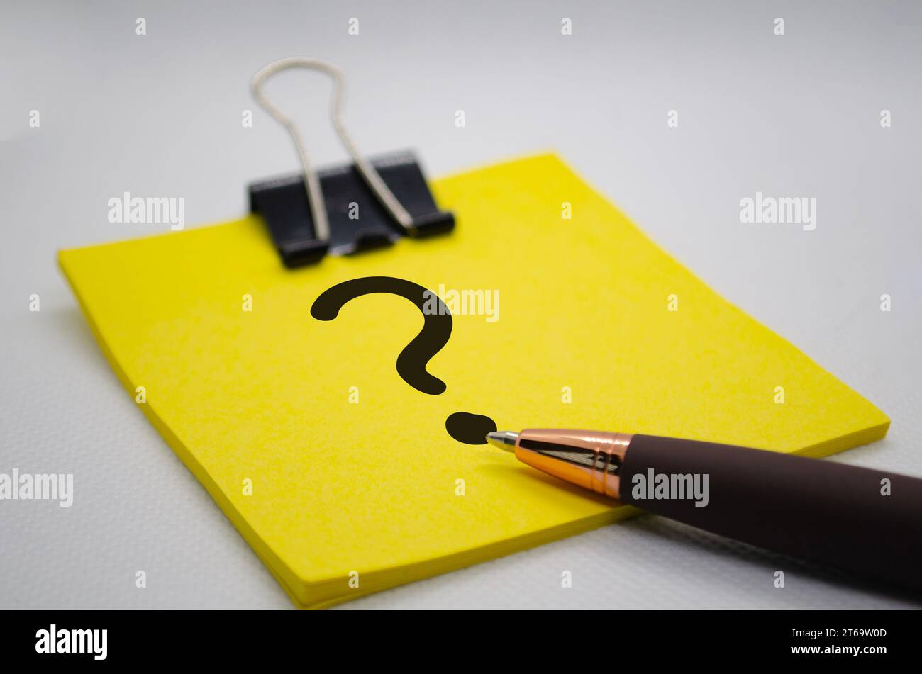 Primo piano del punto interrogativo sul blocco note con la penna su sfondo bianco. Concetto di domande e risposte. Foto Stock
