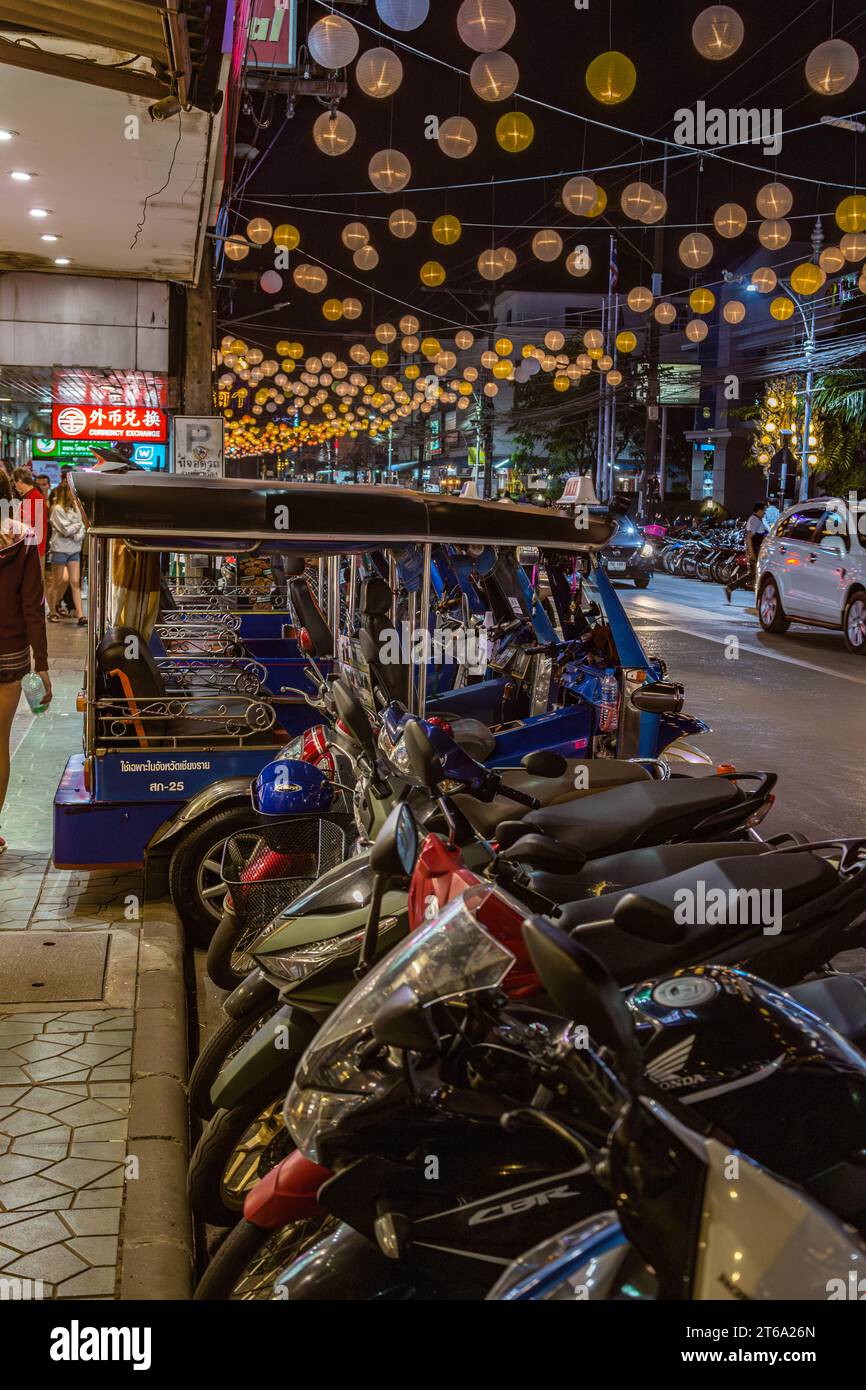 Scooter e taxi ciclabili costeggiano il lato della strada del centro di Chiang Rai, Thailandia Foto Stock