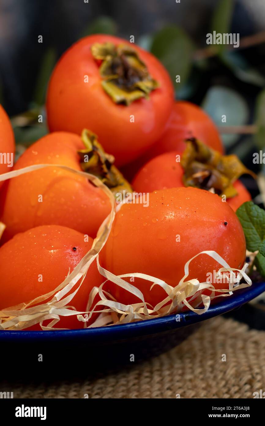 Cachi su sfondo scuro. Frutta fresca matura su un piatto blu e in scatola. Mangiare sano. Foto Stock