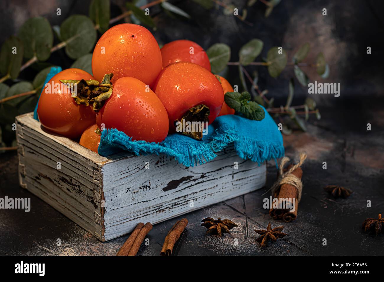 Cachi su sfondo scuro. Frutta fresca matura su un piatto blu e in scatola. Mangiare sano. Foto Stock