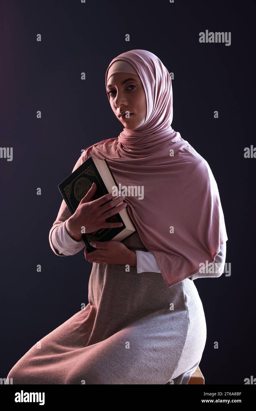 Corano, religione e ritratto di una donna musulmana in uno studio con abiti tradizionali e hijab. Seria, fede e giovane donna islamica persona con il Foto Stock