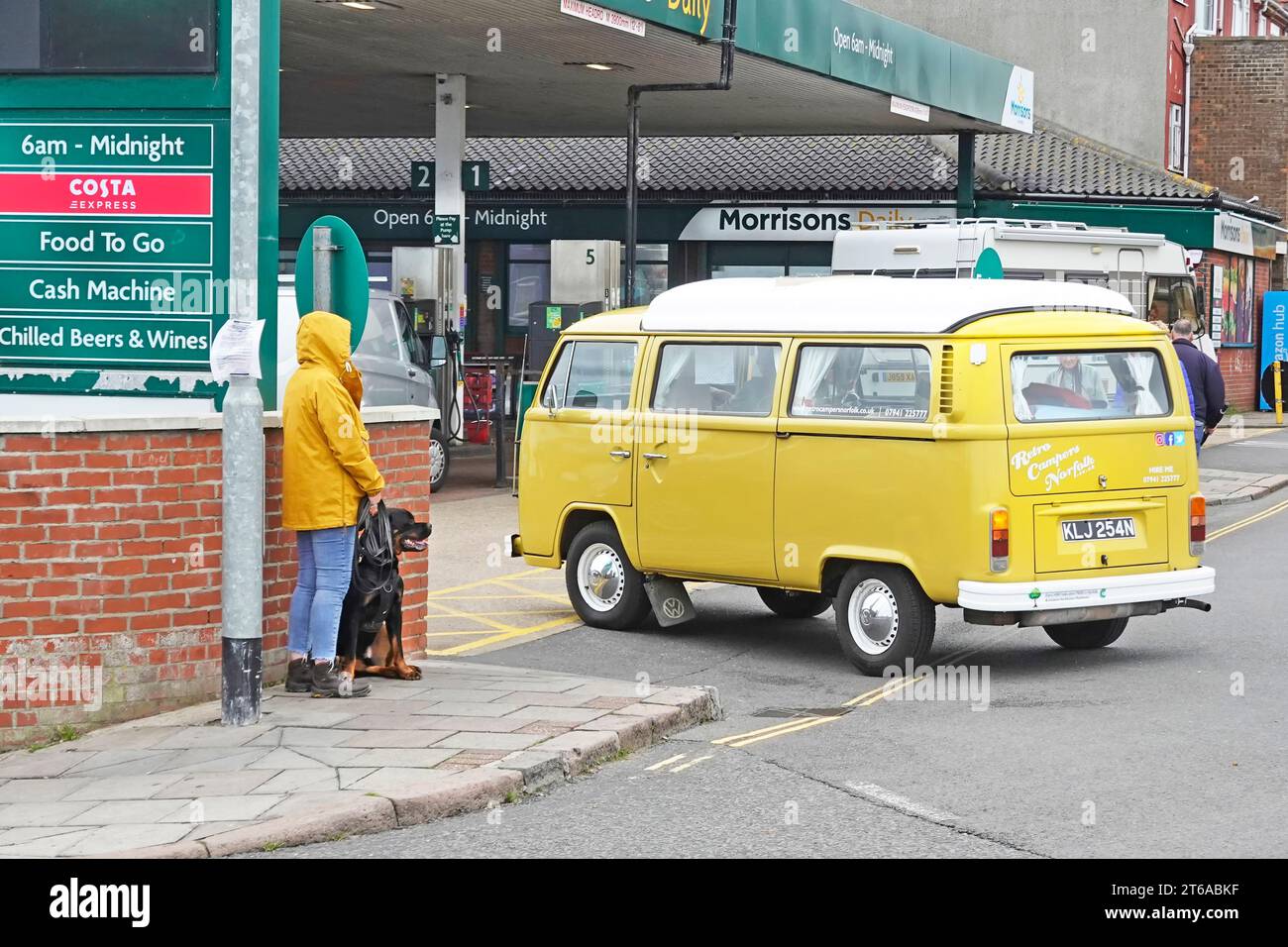 Morrisons Daily Shop e stazione di rifornimento carburante crossover e negozio di cibo da asporto VW Volkswagen camper gialli, camper, camper, camper e cani che aspettano di attraversare Cromer UK Foto Stock