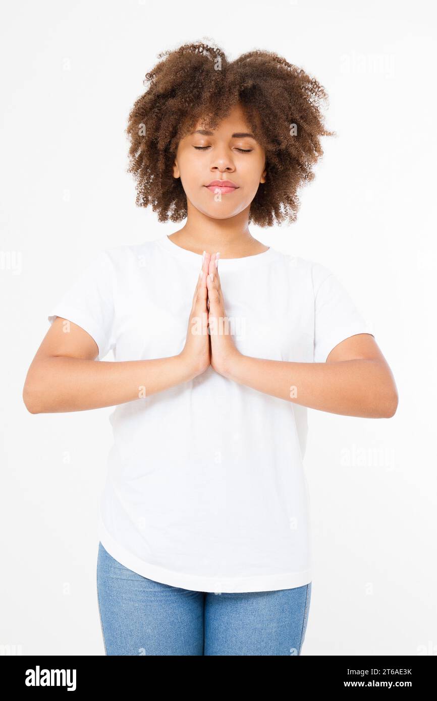 Primo piano delle mani di una donna afro-americana nera in abiti bianchi che meditano al chiuso, concentrati sulle braccia nel gesto di Namaste. Concetto di stile di vita sano. Finto Foto Stock