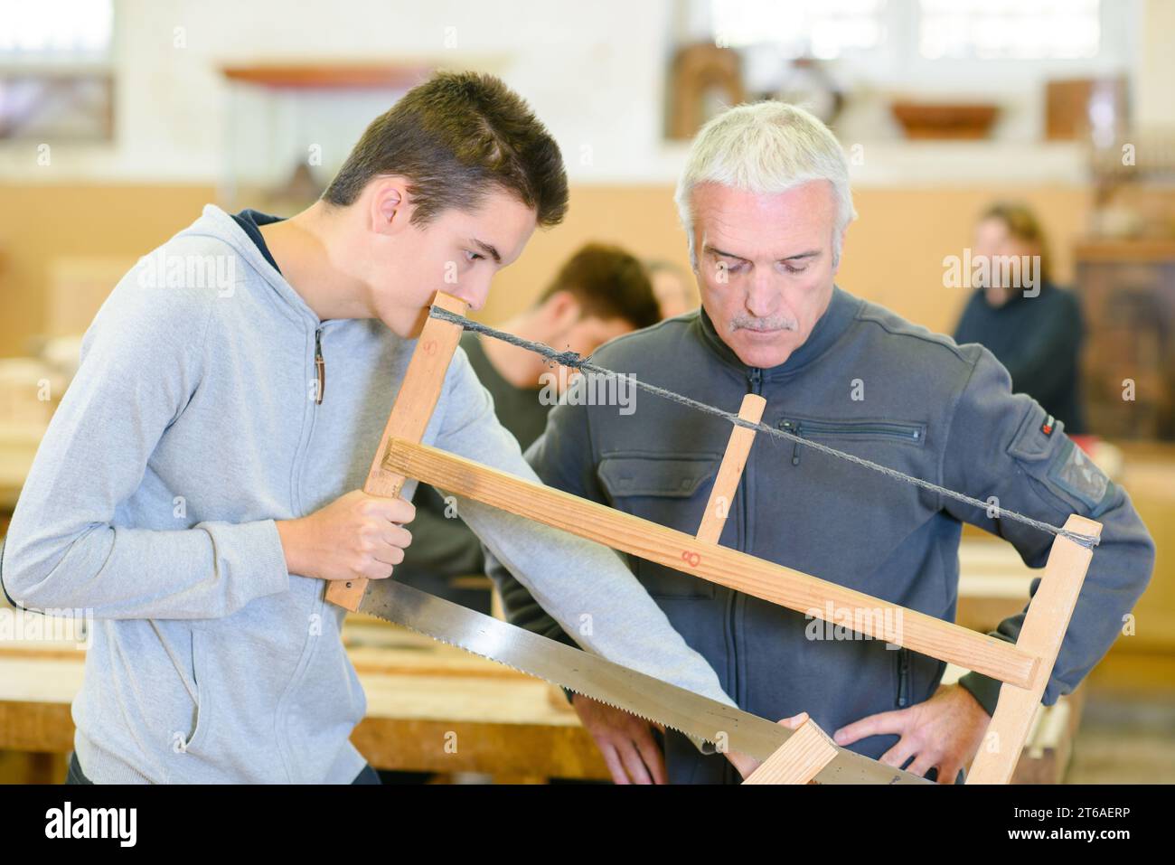 il giovane impara dal maestro liutaio nella lezione di saw Foto Stock