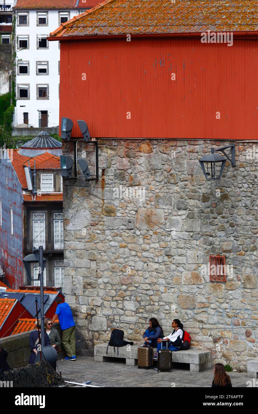Turisti donne con valigie sedute su panchina di pietra accanto al punto panoramico di Miradouro da Rua das Aldas, quartiere di Ribeira, Porto / Oporto, Portogallo Foto Stock