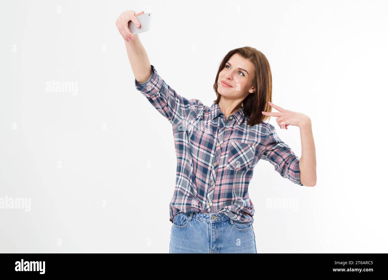 Selfie di bella cute elegante flirty allegra bella adorabile ragazza donna bruna con capelli lunghi in maglietta casual denim, mostrando due dita, Foto Stock