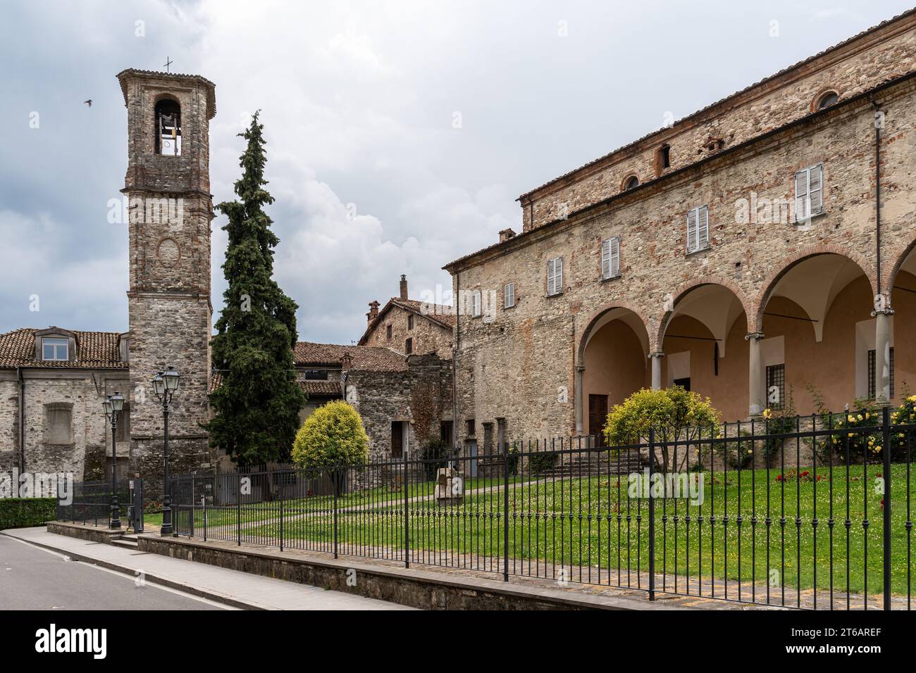 Un classico edificio in pietra con una grande torre dell'orologio sullo sfondo, che mostra uno stile architettonico senza tempo in Italia Foto Stock
